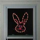 A pink window silhouette decoration for Easter. Designed to look like a cute bunny head with blue eyes and a red nose