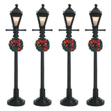 Set of 4 Lemax village lampposts. Each is decorated with a Christmas wreath.