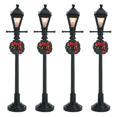 Set of 4 Lemax village lampposts. Each is decorated with a Christmas wreath.