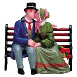 Village accent for a Lemax display. Designed to look like a man and a woman dressed in Victorian-era clothing, sharing a kiss on a wooden bench.