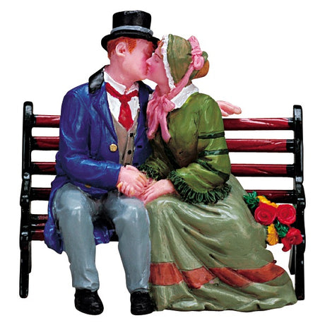 Village accent for a Lemax display. Designed to look like a man and a woman dressed in Victorian-era clothing, sharing a kiss on a wooden bench.