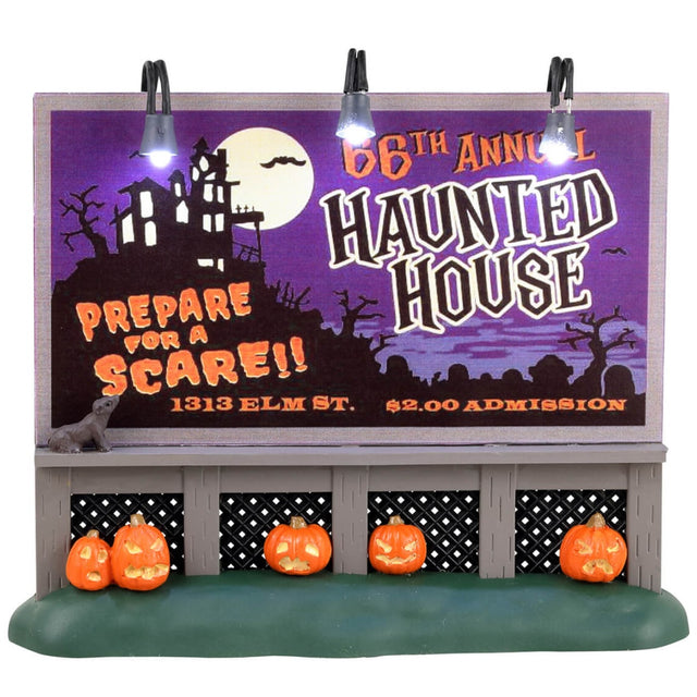 Plastic village accessory for a Spooky Town Lemax display. Designed to look like a billboard on a grassy patch. The billboard is purple and features a cartoon depiction of a haunted house on a hill above a cemetery. The billboard reads "66th Annual Haunted House. Prepare for a scare!! 1313 Elm St. $2.00 admission." There are carved jack-o-lanterns underneath the billboard.