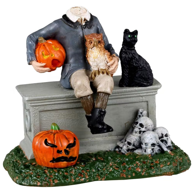 Resin figurine for a Lemax Spooky Town display. Designed to look like a headless boy sitting on top of a coffin. He's holding a carved pumpkin and an owl. There's a black cat with green eyes next to him. There's a jack-o-lantern on the ground and a pile of skulls.
