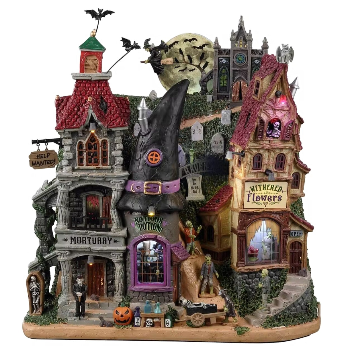 Resin building facade for a Spooky Town Lemax display. Designed to look like a bunch of store fronts. One section is a mortuary with a "help wanted" sign hanging from it. The building next to it reads "NOTION'S POTIONS" and has a witch hat for a roof. The building next to it is a flower shop. Behind them all is a cemetery and a spooky cathedral. There's a witch flying near the moon with bats following behind.