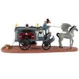 Resin table accent for a Lemax Spooky Town Village display. Designed to look like a wagon carrying a coffin. The wagon is being pulled by a horse with wings. There's a vampire couple that have just gotten married standing outside.