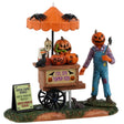 Resin table accent for a Lemax display. Designed to look like a scarecrow with a pumpkin head standing in front of a cart full of carved pumpkins. There's an orange umbrella above the cart with spiders on top. There's a sign on the ground that reads "Fried crow wings, moldy pumpkin bread and rancid pumpkin seeds."