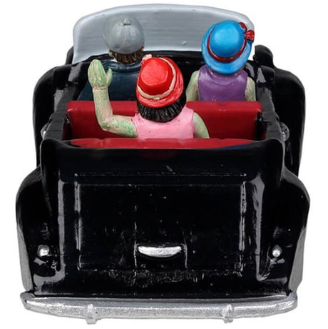 Resin village accent for a Lemax Spooky Town display. Designed to look like three people in a shiny, black convertible car. They're all dressed up. The driver is wearing a suit and a gray hat. The woman in the passenger seat is wearing a purple dress and a blue hat. The woman in the backseat is wearing a pink dress, a pearl necklace and a red hat. Their skin is green.
