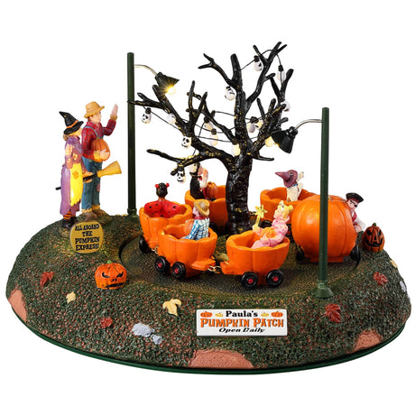 Resin table accent for a Lemax display. Designed to look like a carnival ride for kids. The carts are shaped like pumpkins. There are skull lights hanging from a bare tree and parents waving at their kids in the ride. There's a sign on the side that reads "ALL ABOARD THE PUMPKIN EXPRESS."