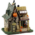 Porcelain lighted building for a Lemax display. Designed to look like a creepy cabin with bales of hay on the roof and on the columns holding it up. There's a skeleton sitting on the porch.