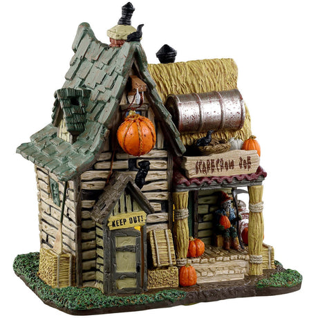 Porcelain lighted building for a Lemax display. Designed to look like a creepy cabin with bales of hay on the roof and on the columns holding it up. There's a skeleton sitting on the porch.