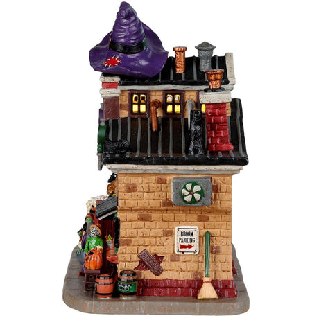 Porcelain lighted building for a Lemax display. Designed to look like a large, brick bar. There are three witches standing on front of a cauldron. There are barrels of beer. There's a window leading to the bar and a skeleton ordering drinks. There are pumpkin lights and a giant purple witch hat on the roof.