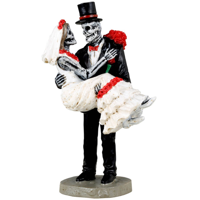 Resin figurine for a Lemax Spooky Town display. Designed to look like a skeleton couple that just got married. He's wearing a black tuxedo and a red bow tie. She's wearing a wedding dress and holding red flowers. He's holding her in his arms.