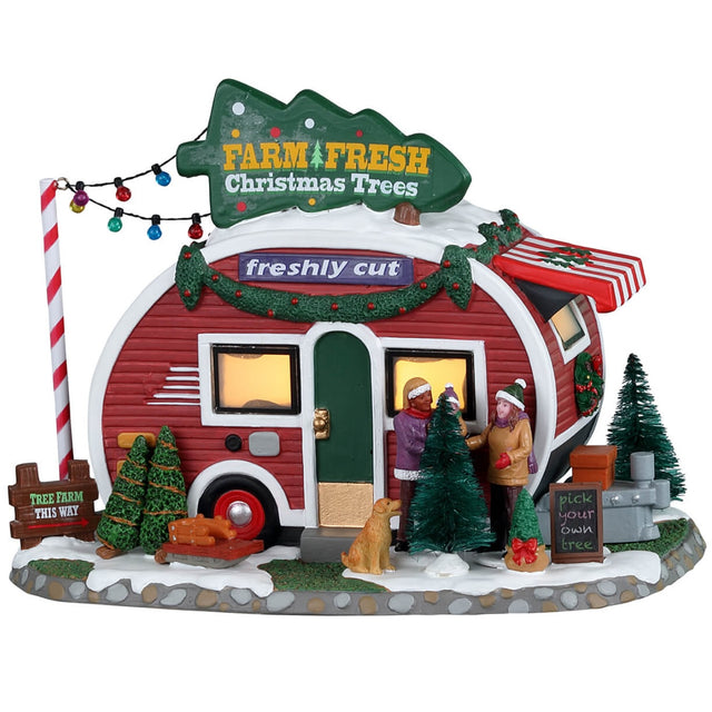Porcelain lighted building for a Lemax display. Designed to look like a small red and white camper that's selling fresh Christmas trees. There are two people and a puppy checking out some of the trees outside.