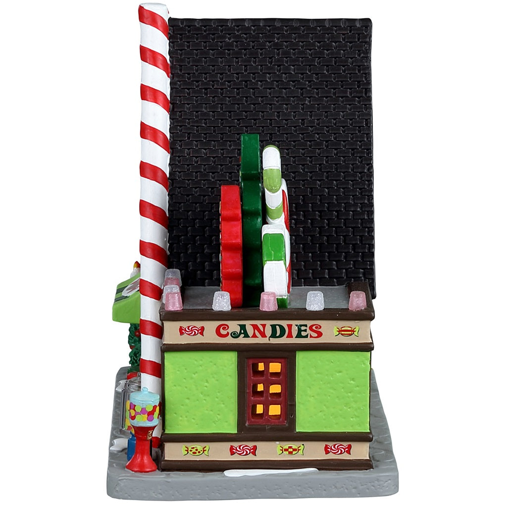 Porcelain lighted building for a Lemax display. Designed to look like an A-frame candy shop. There's a large gingerbread cookie statue on the left and a bunch of large cookie and candy cane statues on the right side. There are potted plants and gumball machine accents.