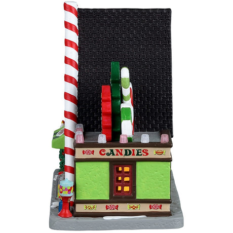 Porcelain lighted building for a Lemax display. Designed to look like an A-frame candy shop. There's a large gingerbread cookie statue on the left and a bunch of large cookie and candy cane statues on the right side. There are potted plants and gumball machine accents.