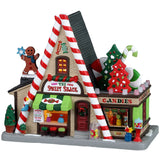 Porcelain lighted building for a Lemax display. Designed to look like an A-frame candy shop. There's a large gingerbread cookie statue on the left and a bunch of large cookie and candy cane statues on the right side. There are potted plants and gumball machine accents.
