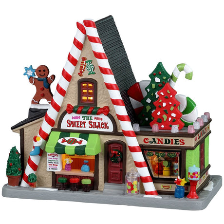 Porcelain lighted building for a Lemax display. Designed to look like an A-frame candy shop. There's a large gingerbread cookie statue on the left and a bunch of large cookie and candy cane statues on the right side. There are potted plants and gumball machine accents.