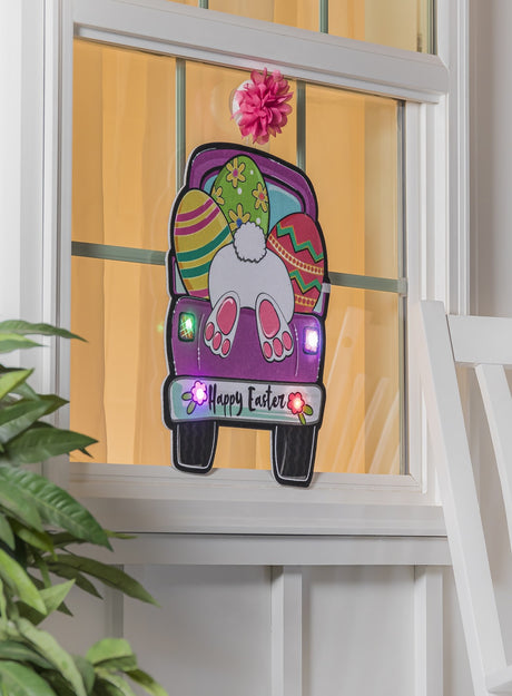 A mat for your front door that reads "Happy Easter" and features a cute bunny butt sticking out of the back of a pink truck carrying three multi-colored eggs. The lights on the truck and the flowers on the bumper light up. This is what it would look like on your door