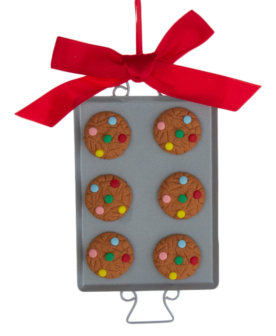 Ornaments shaped like cookies with M&M candies on them, resting on silver trays.