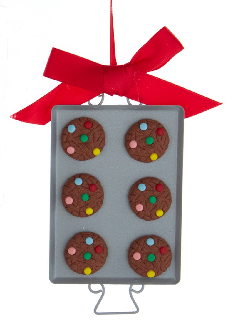 Ornaments shaped like cookies with M&M candies on them, resting on silver trays.