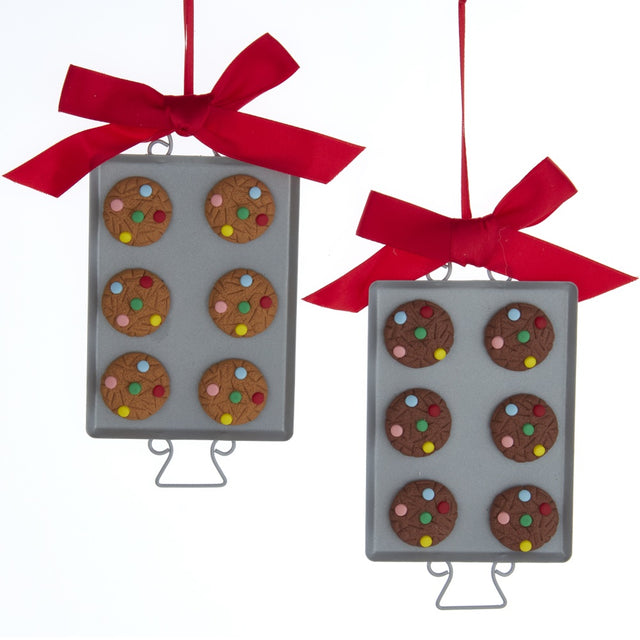 Ornaments shaped like cookies with M&M candies on them, resting on silver trays.
