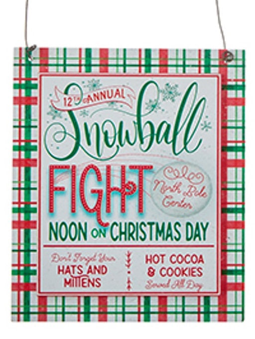 Sign reads "12th Annual Snowball Fight at the North Pole Center. Noon on Christmas Day. Don't forget your hats and mittens. Hot cocoa and cookies served all day."