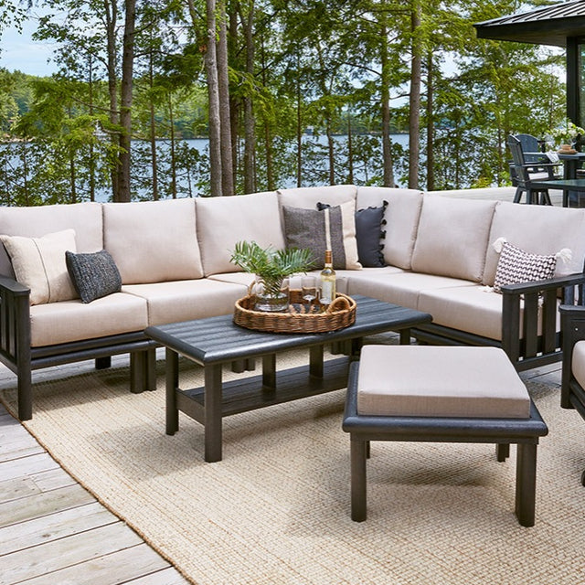 A resin patio furniture collection on a porch near a body of water