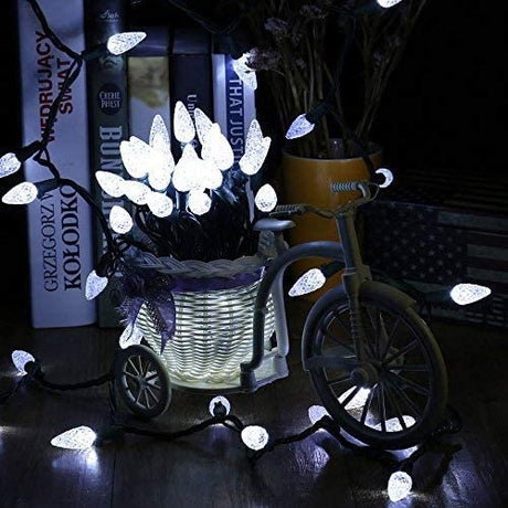 A string of pure white LED lights inside the basket of a small, decorative bike on a bookshelf.