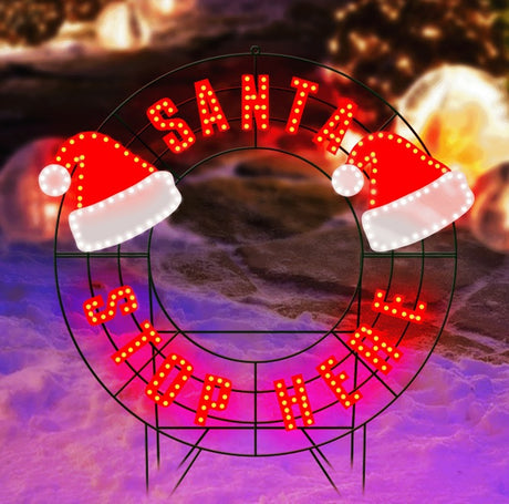 LED outdoor decoration that reads "Santa Stop Here." The text is red. It also features two Santa hats.