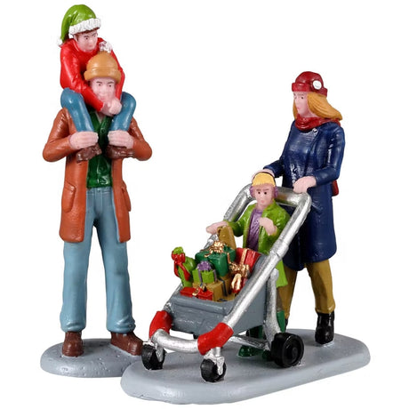 Resin figurines for a Lemax display. One figure is designed to look like a dad holding a child on his shoulders. The other figure is of a mom pushing a stroller full of presents with another child in front of her. They're all wearing winter clothes.
