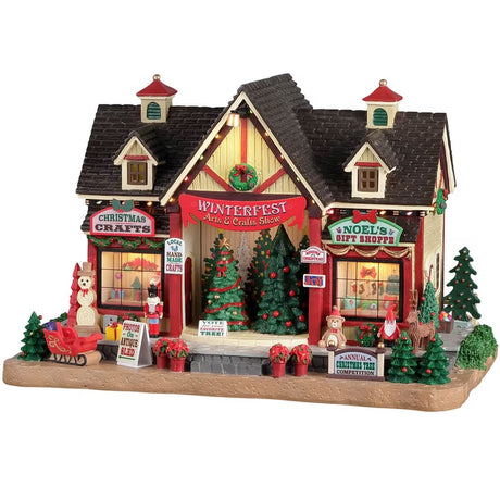 Resin lighted building for a Lemax display. Designed to look like an arts and crafts venue decorated for Christmas. There are decorated Christmas trees on stage for you to vote for your favorite. There's a Christmas crafts shop and a gift shop. There are poinsettia, sleighs, presents, a snowman, a teddy bear, an elf and a reindeer.