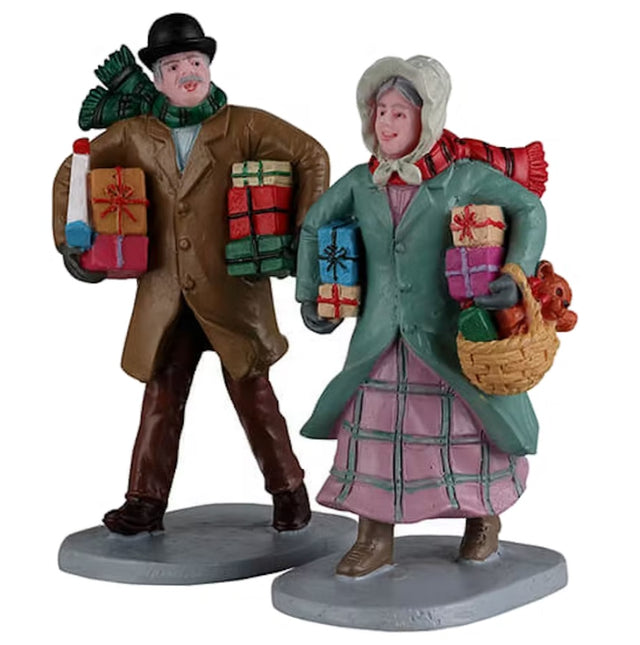 Resin figurines for a Lemax Village tabletop display. Designed to look like a man and a woman dressed in winter clothes and holding lots of presents.