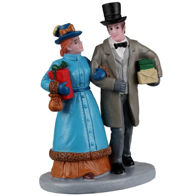 Resin figurine for a Lemax display. Designed to look like a man and a woman walking arm in arm. They're both wearing older Victorian-era type clothes and holding presents.