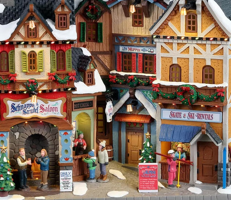 Resin building facade for a Lemax display. Designed to look like a bunch of different store fronts. There's a salon, a hot cocoa booth, a muffin shop and a skate/ski rental shop. It's decorated for Christmas and there's snow on the roof and sidewalk.