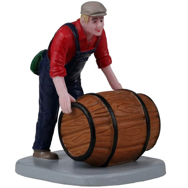 Resin figurine for a Lemax display. Designed to look like a man wearing overalls rolling a barrel. He has blonde hair and is wearing a hat.