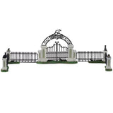 Polyresin village accessory for a Lemax display. Designed to look like an iron fence on patches of grass. There are four columns with witch hat and black cat statues on top. The gate reads "Witch's Gate" and there's a broom leaning against it.