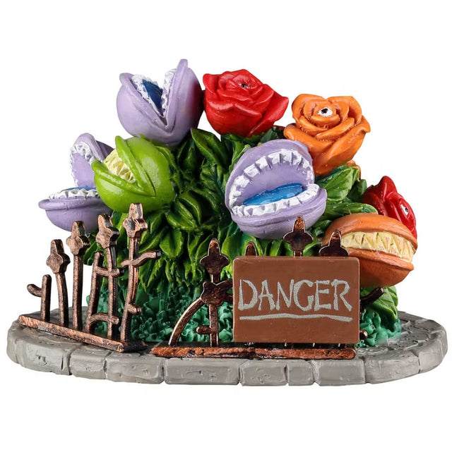 Resin village accessory for a Spooky Town Lemax display. Designed to look like a small garden full of plants that are alive. There's a small bronze fence and a brown sign that reads "DANGER." The purple and green flowers have teeth. The red and the orange flowers have an eye in the middle.