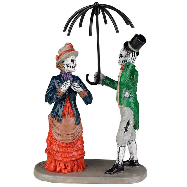Polyresin figurines for a Lemax Spooky Town display. Designed to look like a skeleton couple wearing old Victorian-era clothes. They're standing underneath a broken umbrella. The woman is wearing an orange dress, a blue jacket and a purple scarf. The man is wearing a green suit jacket, gray pants and a black top hat.