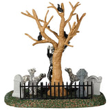 Resin village accent for a Lemax display. Designed to look like a skeleton dancing in a graveyard. There are tombstones and carved pumpkins on the grass. There's also a bare tree with crows on the branches. There are also skeleton dogs.