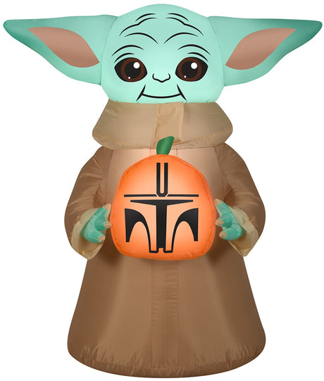 Halloween inflatable decoration shaped like baby Grogu from the show The Mandalorian. He's holding a small pumpkin that's been carved to look like a Mandalorian helmet.
