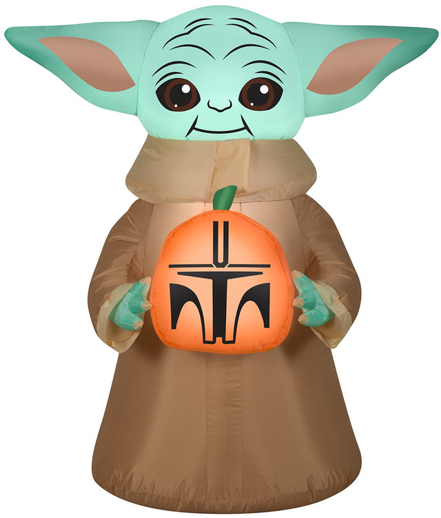 Halloween inflatable decoration shaped like baby Grogu from the show The Mandalorian. He's holding a small pumpkin that's been carved to look like a Mandalorian helmet.