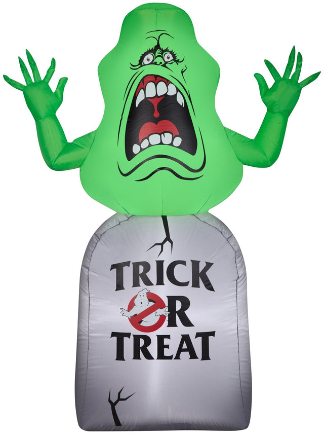 Inflatable Halloween decoration shaped like Slimer, the green ghost from the movie Ghostbusters. He appears to be jumping out from a tombstone that reads "Trick or Treat" and features the Ghostbusters logo.