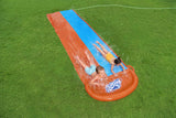 A slip n slide with two lanes that lead into a splash pad.