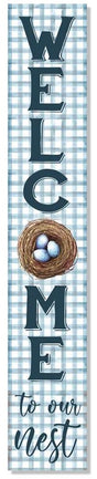 A vertical porch board that reads "Welcome to our Nest" on a light blue and white background. The O is a nest with three eggs in it. The text is a dark teal color. "WELCOME" is in skinny block letters and "to our nest" is in cursive