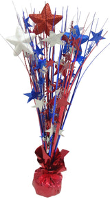 Patriotic tabletop decoration with a shiny, red tinsel base. Coming out of the base, there's red, white and blue tinsel with red, white and blue tinsel stars as well as foam stars with blue, red and white glitter.