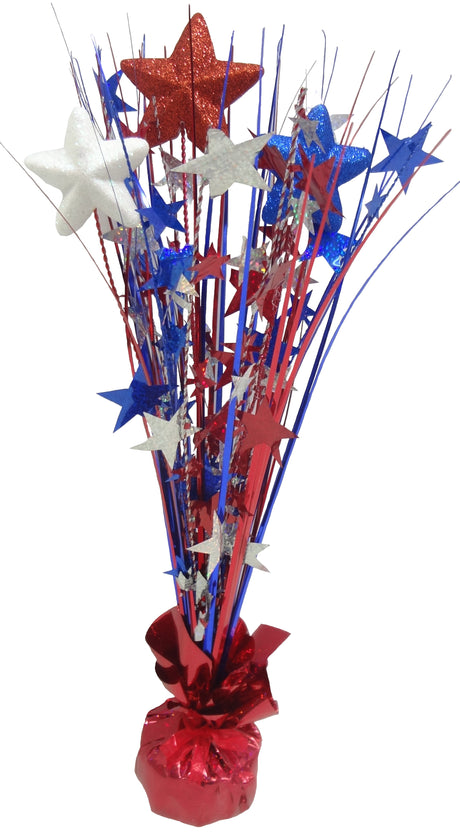 Patriotic tabletop decoration with a shiny, red tinsel base. Coming out of the base, there's red, white and blue tinsel with red, white and blue tinsel stars as well as foam stars with blue, red and white glitter.