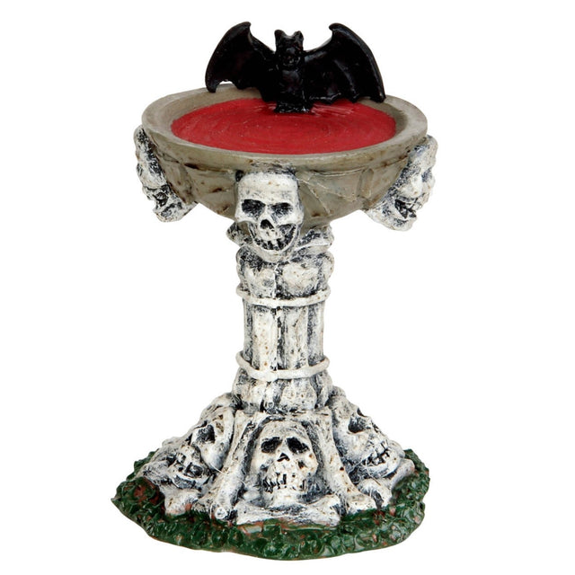 Polyresin figurine for a Lemax display. Designed to look like a birdbath made out of skulls and bones. There's a bat drinking from it and it looks like the birdbath is filled with blood.