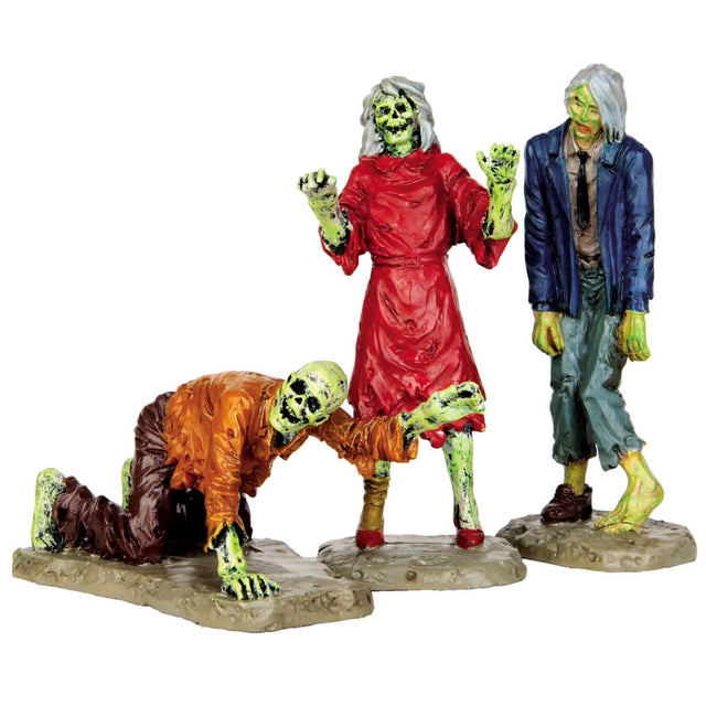 Polyresin figurines for a Lemax Spooky Town display. Designed to look like three zombies. One zombie is crawling on the ground and wearing an orange shirt and brown pants. Another zombie is wearing a red dress and red high heels. The other zombie is wearing a blue suit jacket, a tan shirt, a black tie, teal pants and one brown shoe.