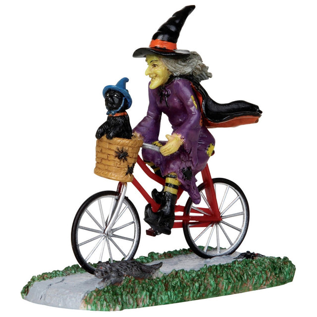 Polyresin figurine for a Lemax Spooky Town display. Designed to look like a witch on a bicycle. She's wearing a black witch hat, a black and orange cape and a purple dress. The bike is red and has a basket in the front with spiders on it. Inside the basket is a black cat wearing a blue witch hat and an orange collar.