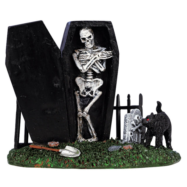 Polyresin figurine for a Lemax display. Designed to look like part of a graveyard. There's a black coffin with a skeleton leaning up against a metal fence. There's a shovel and a black cat smelling a tombstone.